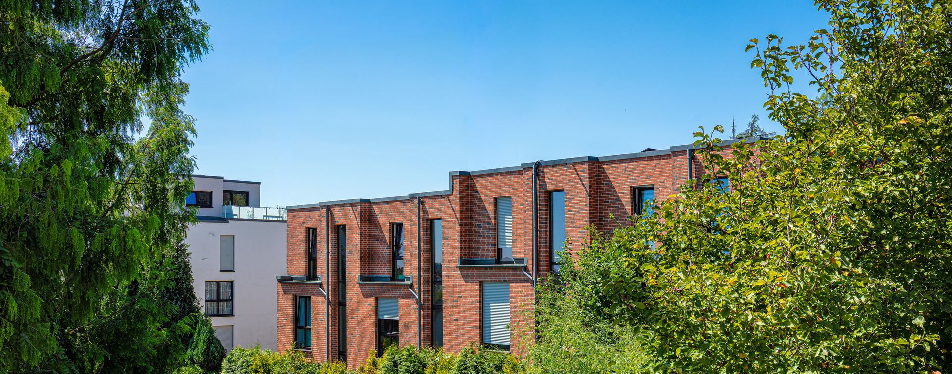 Reihenhäuser in Klinkerbauweise mit Mehrfamilienhaus im Hintergrund – realisiertes Projekt von Soltwisch Architektur